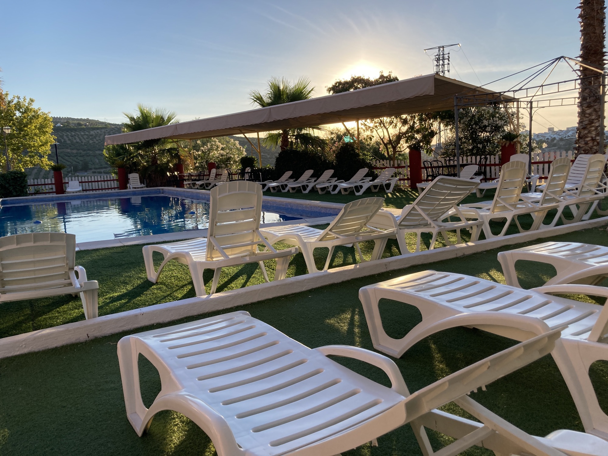 Piscina exterior de temporada con tumbonas y zonas de sombra